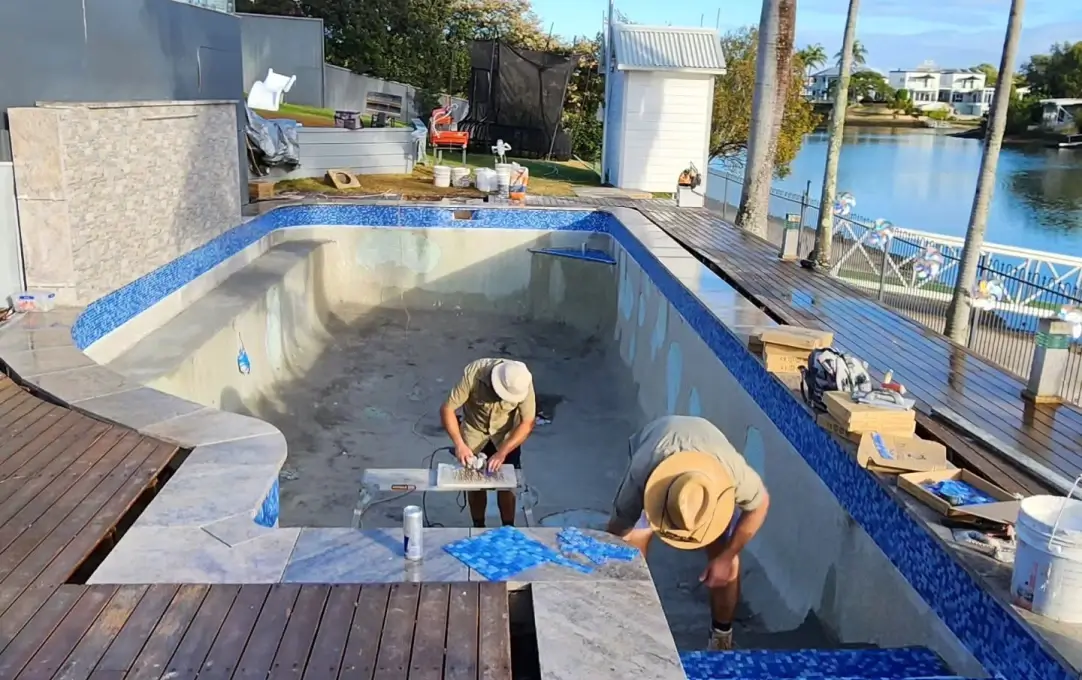 concrete pool builders performing pool tiling at this home in Mermaid Waterss concrete pool builders performing pool tiling at this home in Mermaid Waterss